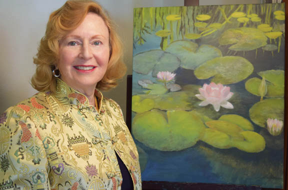 Verlaine Crawford standing next to her painting, Lotus Pond at the Mission San Juan Capistrano.